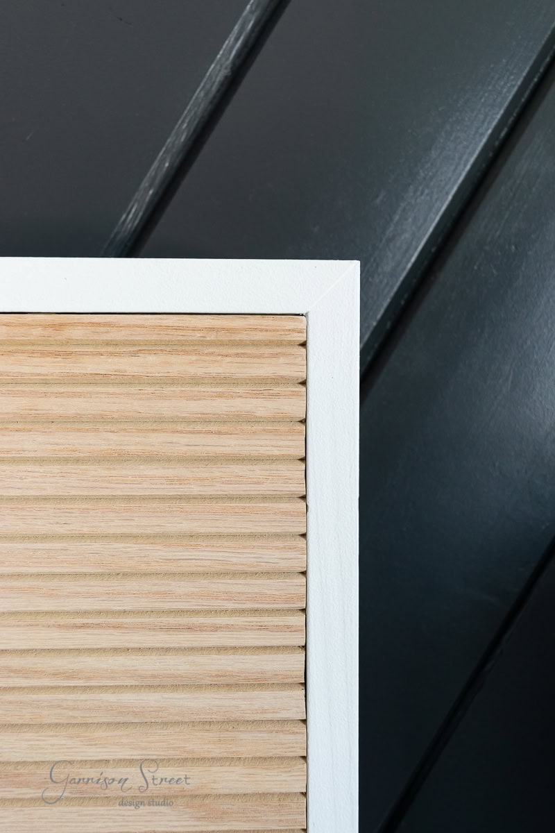 A close-up of an adjustable base section of a wall featuring light wood slats in a white frame against a dark, diagonally paneled background. The image includes a subtle watermark with text in the bottom-left corner, blending seamlessly like the perfect bed frame for your room.