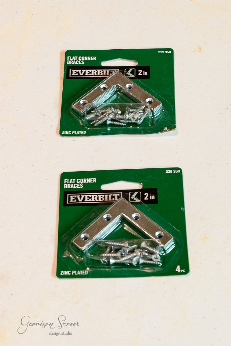 Two green packages of Everbilt flat corner braces are displayed, perfect for assembling your IKEA Malm or reinforcing a dog crate. Each package contains metal brackets and screws, with the size noted as 2 inches and featuring a sturdy zinc plating.
