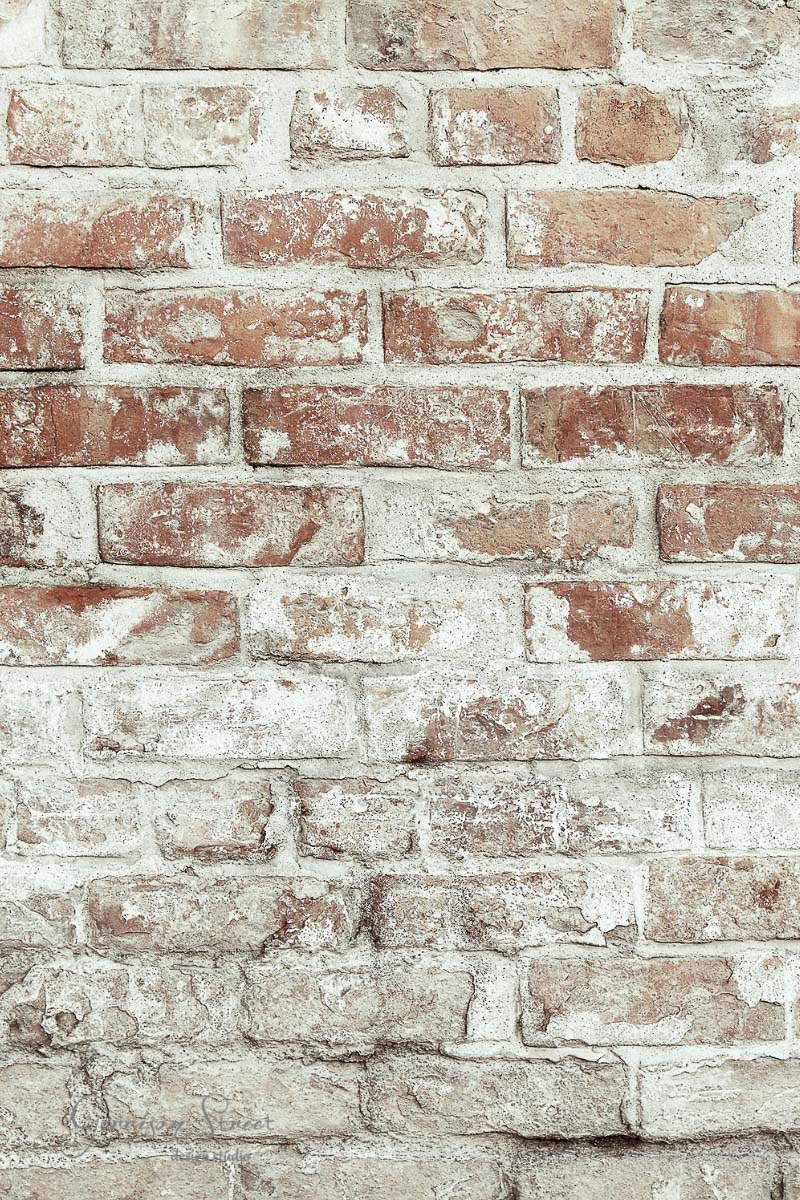 An aged brick wall with a textured surface, featuring a mix of faded red and white bricks, offers rustic basement wall ideas that go beyond drywall for a charmingly rugged appearance.