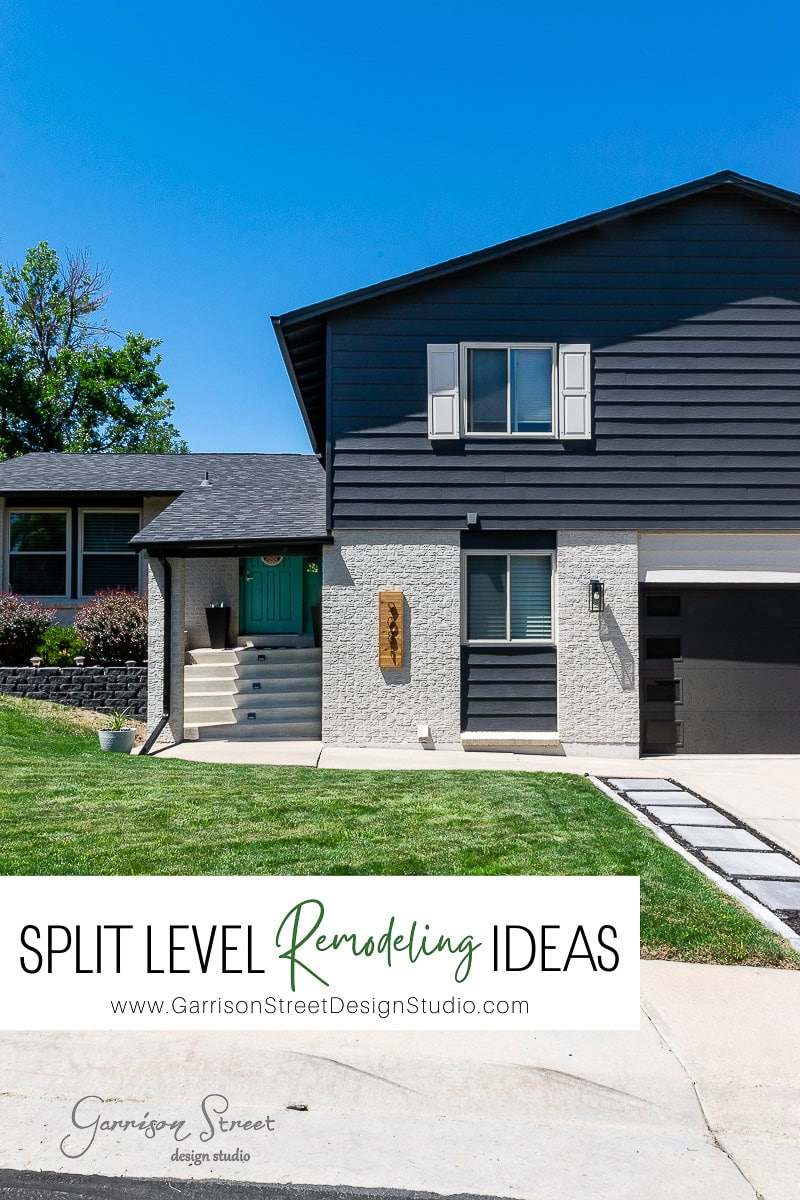 Modern split-level home with dark gray siding and a turquoise front door. A sign beside the door reads "Remodeling Ideas for Split Level Houses." The garage is on the right, and there's a lush lawn with a tree on the left. Clear blue sky overhead.