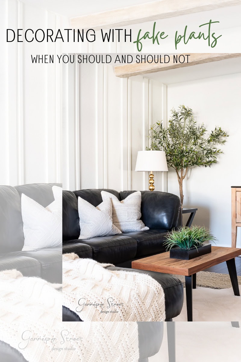 Stylish living room with a black leather sofa, white pillows, and a light throw blanket. A wooden coffee table features a small green plant. A lamp and a tall artificial tree. Text reads: "Decorating with fake plants: when you should and should not."