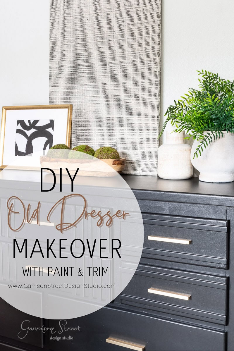 A black dresser DIY makeover with modern painting and trim. Decor includes a green plant, a framed abstract art piece, and decorative moss balls. Text reads "DIY Old Dresser Makeover with Paint & Trim" from Garrison Street Design Studio.