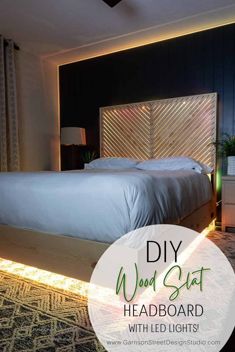 A cozy bedroom showcasing a DIY queen wood slat headboard illuminated by LED lights. The bed is neatly made with a white comforter, and the softly lit room highlights modern decor elements.