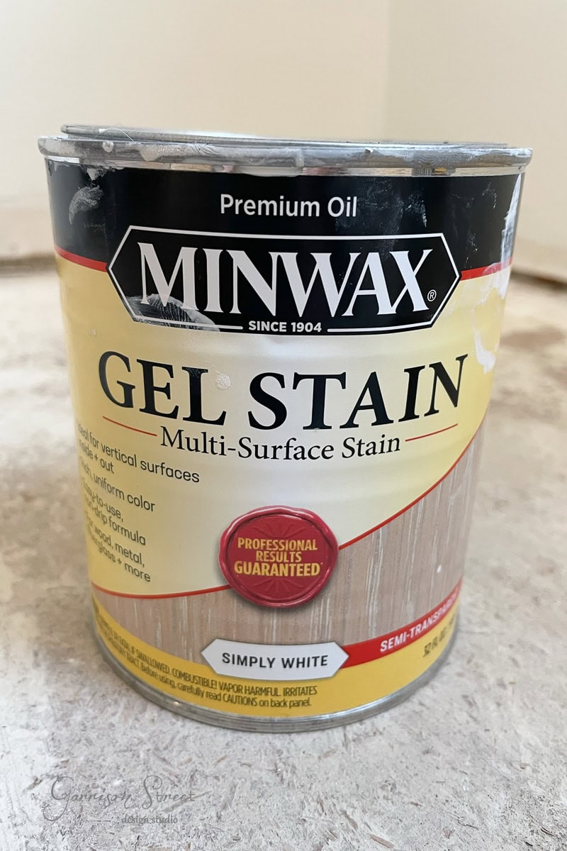 A can of Minwax Premium Oil Gel Stain in Simply White rests on a light-colored surface. The label provides product details and a red badge declaring "Professional Results Guaranteed."
