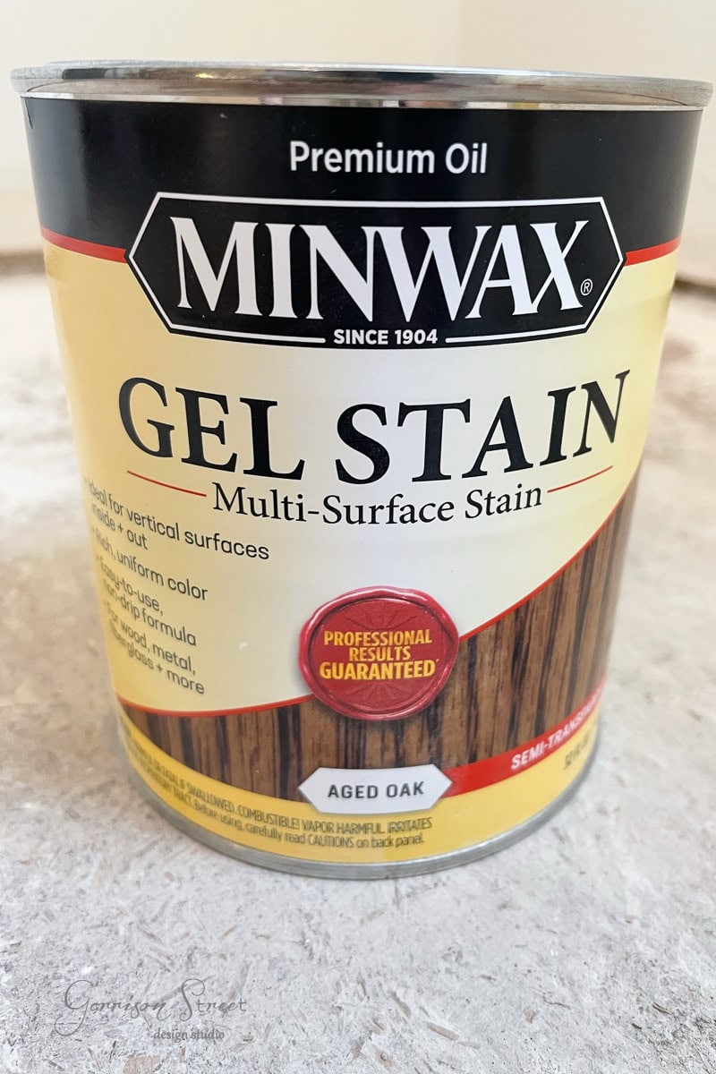 A can of Minwax Premium Oil Gel Stain sits on the counter. The label promises professional results on multiple surfaces, featuring the "Aged Oak" color in a semi-transparent finish.