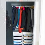 Small coat closet makeover featuring a variety of colorful coats hung on a rod and organized white IKEA TROFAST storage bins below. The image includes text: "DIY Small Coat Closet Makeover with IKEA Trofast Hack - Garrison Street Design Studio.