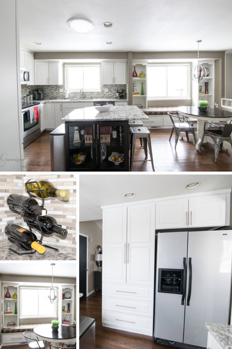 A modern kitchen featuring white cabinets, stainless steel appliances, and a central island with a dark base and granite countertops. There's a built-in bench dining area, a wine rack with bottles, and a large double-door refrigerator.