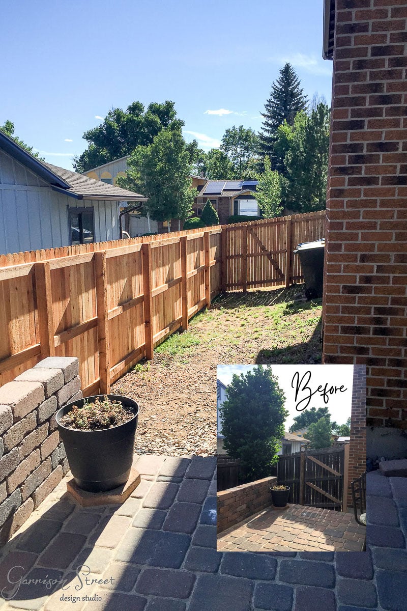 A backyard with new wooden fence and brick patio. A black planter sits on the patio. An inset "before" photo shows the previous chain-link fence and greenery. Sky is clear with trees and houses in the background.