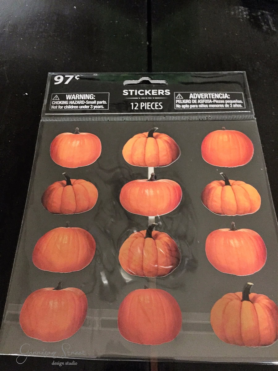 A pack of pumpkin stickers on a black surface. The pack contains 12 pieces displayed in three rows. The price is marked as 97 cents. A choking hazard warning is also visible.
