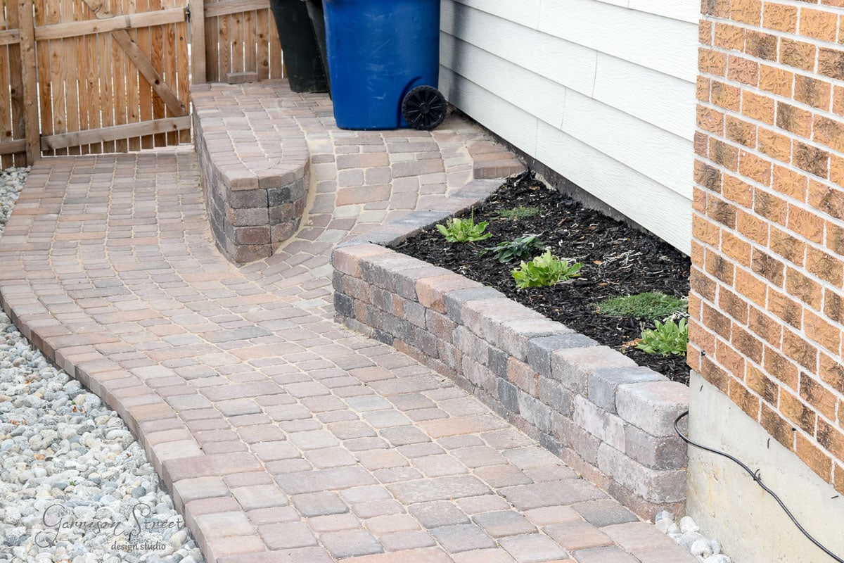The raised planter bed filled in with new plants alongside the stone path.