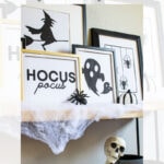A shelf decorated for Halloween with framed black-and-white art of a witch, bats, spiders, and the words "Hocus pocus," fake cobwebs, a small spider, and a skeleton sitting below the shelf.