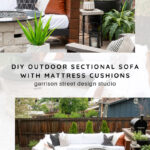 Modern outdoor patio with a white sectional sofa, brown and black cushions, green potted plants, and a round fire pit on a stone patio. Text overlay reads: DIY outdoor sectional sofa with mattress cushions.