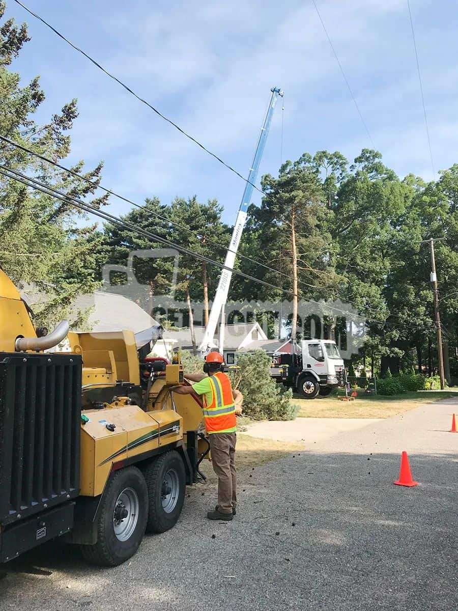 Utility worker in safety gear using crane to work on power lines.