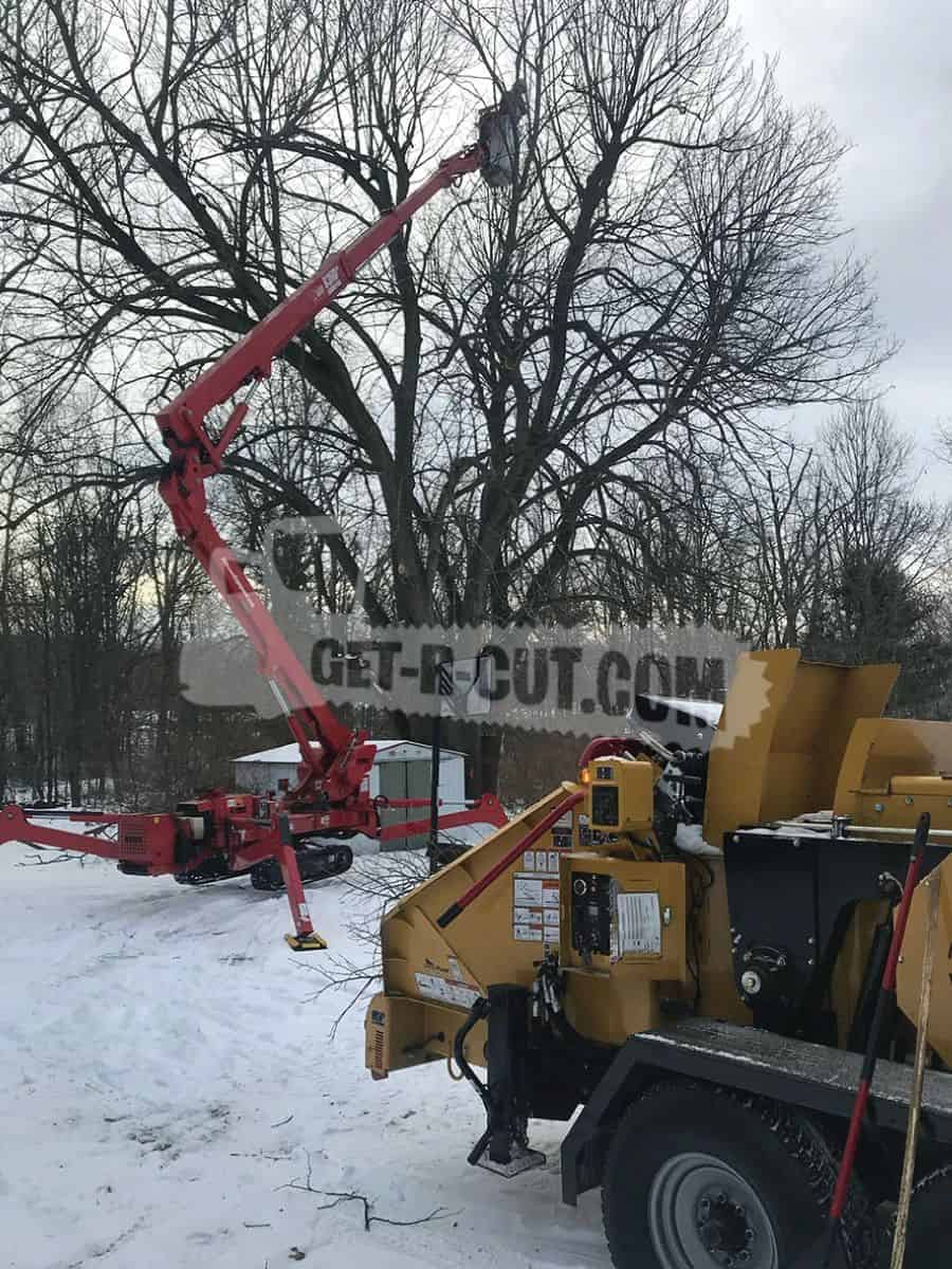 Tree trimming equipment with a cherry picker and wood chipper in snowy outdoor setting.