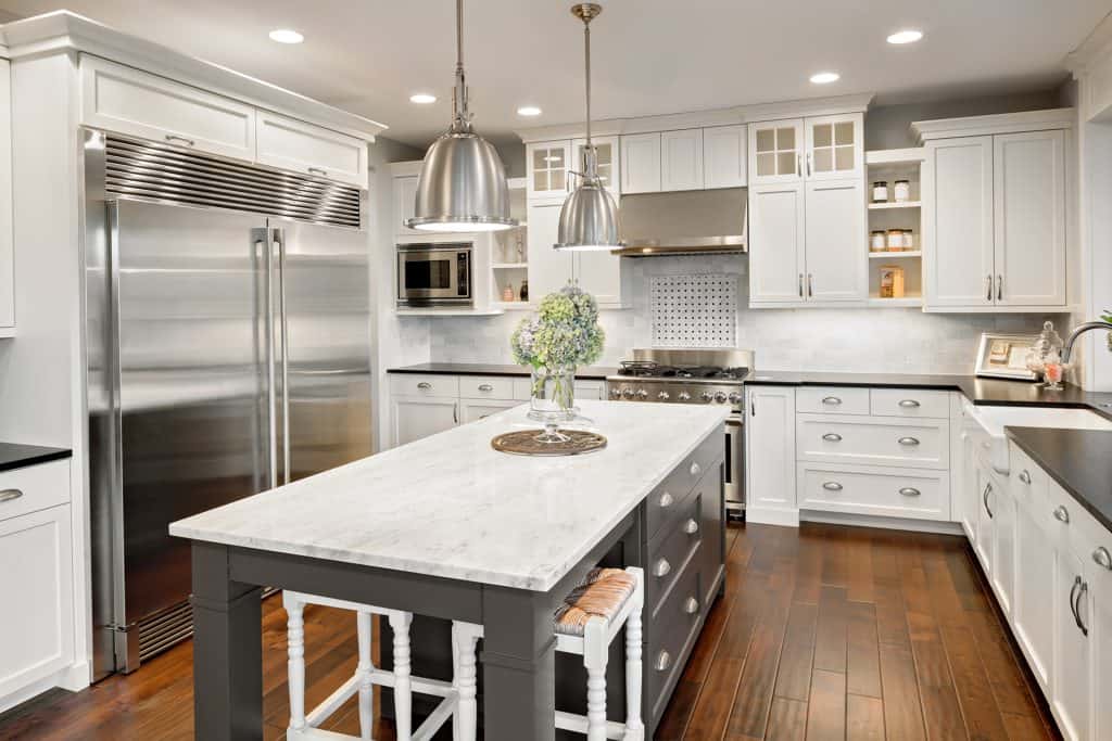 Elegant white kitchen with marble countertops, modern cabinetry, and stainless steel appliances for.