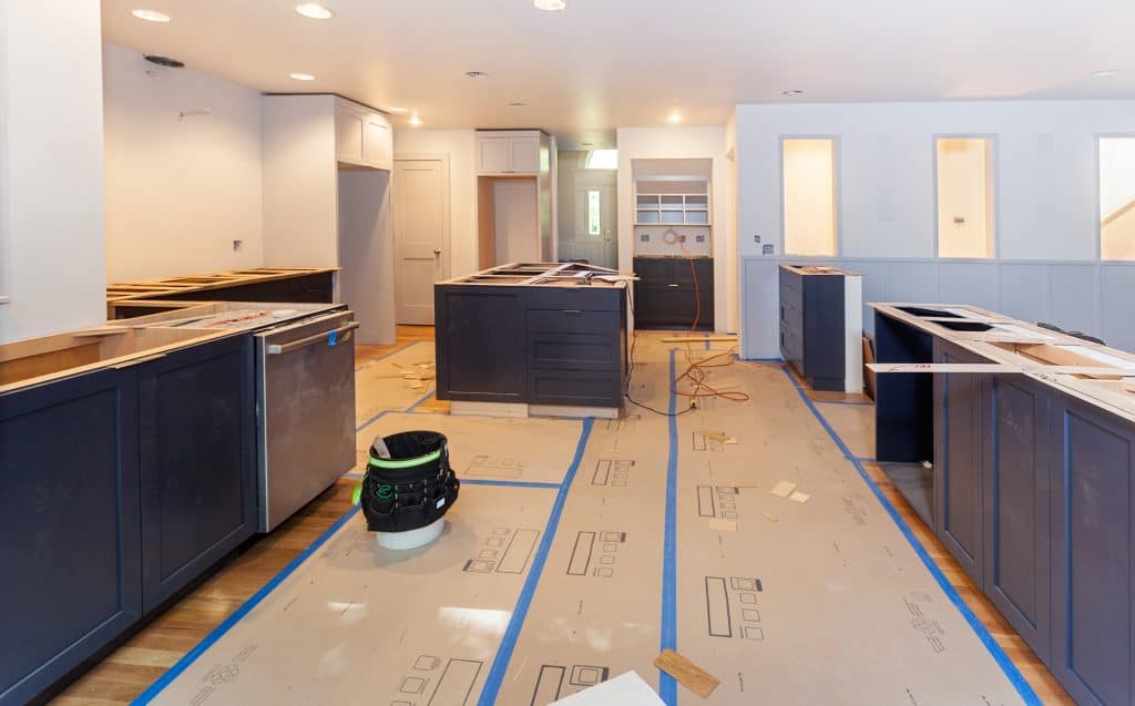 Modern kitchen with dark blue cabinets and new countertops being installed.