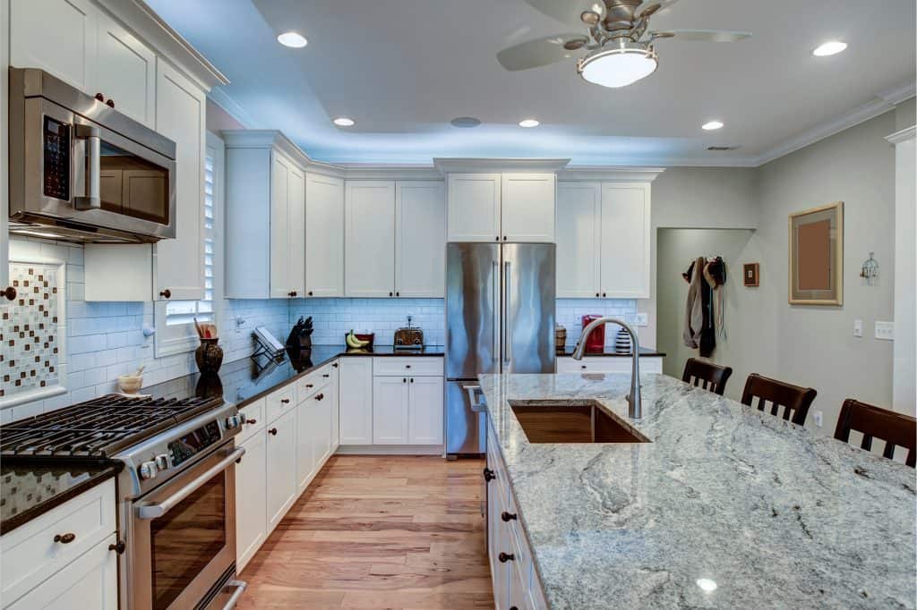 Modern kitchen with white cabinets and granite countertops.