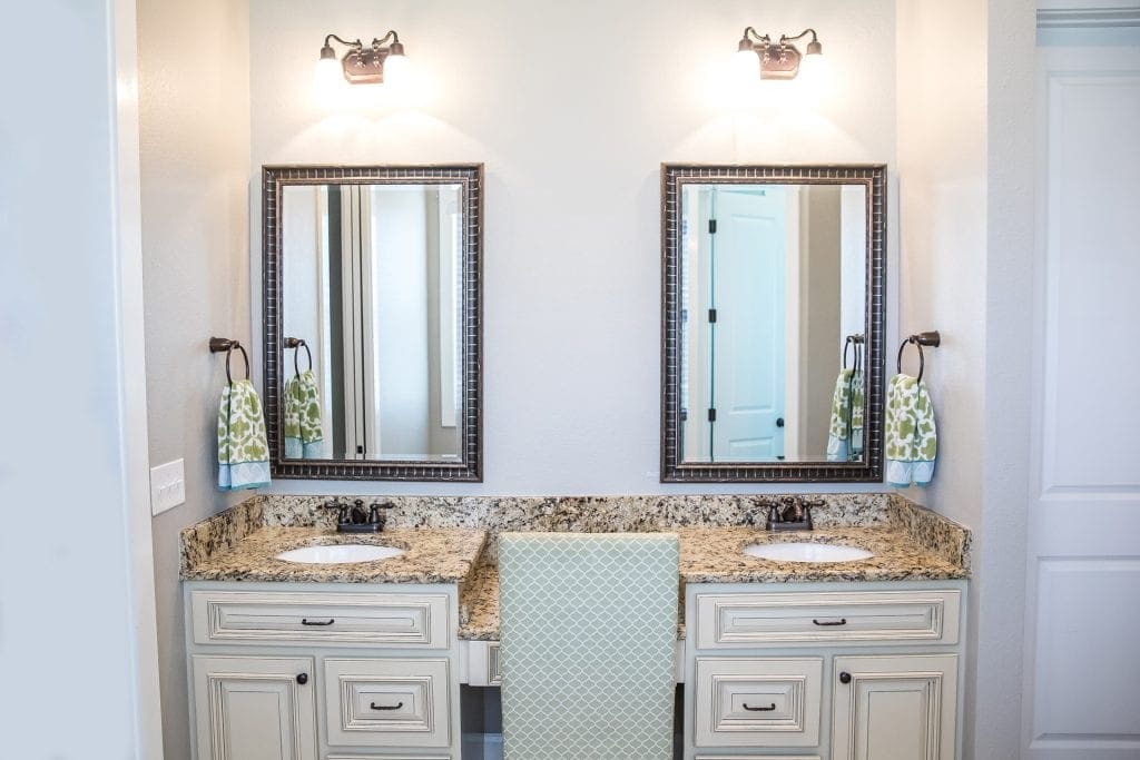 Bathroom vanity with dual mirrors, granite countertops, and modern lighting.