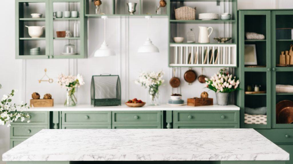 Modern kitchen featuring marble countertops and green cabinetry.