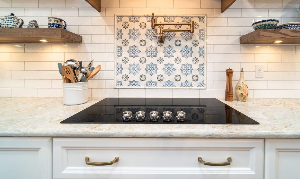 Elegant kitchen countertop with black cooktop and decorative backsplash.
