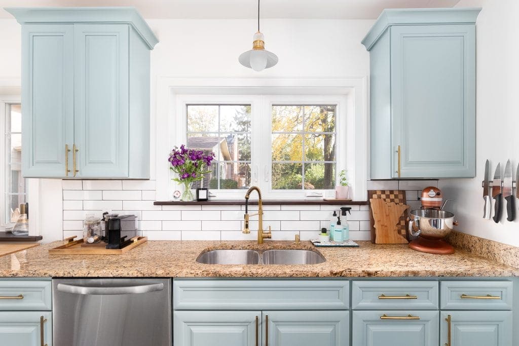 Countertop with granite surface and light blue cabinetry in modern kitchen.