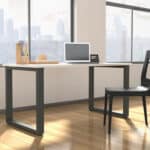 Office desk with computer and chair in front of large window overlooking city skyline.