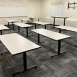 Empty classroom with white tables and whiteboards at Grand River Office.