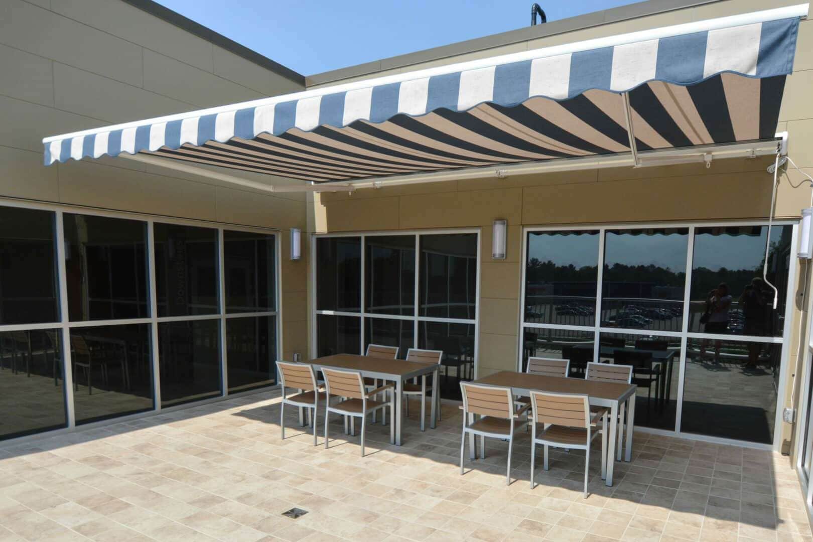 Outdoor patio with tables and chairs under a striped awning at Grand River Office.