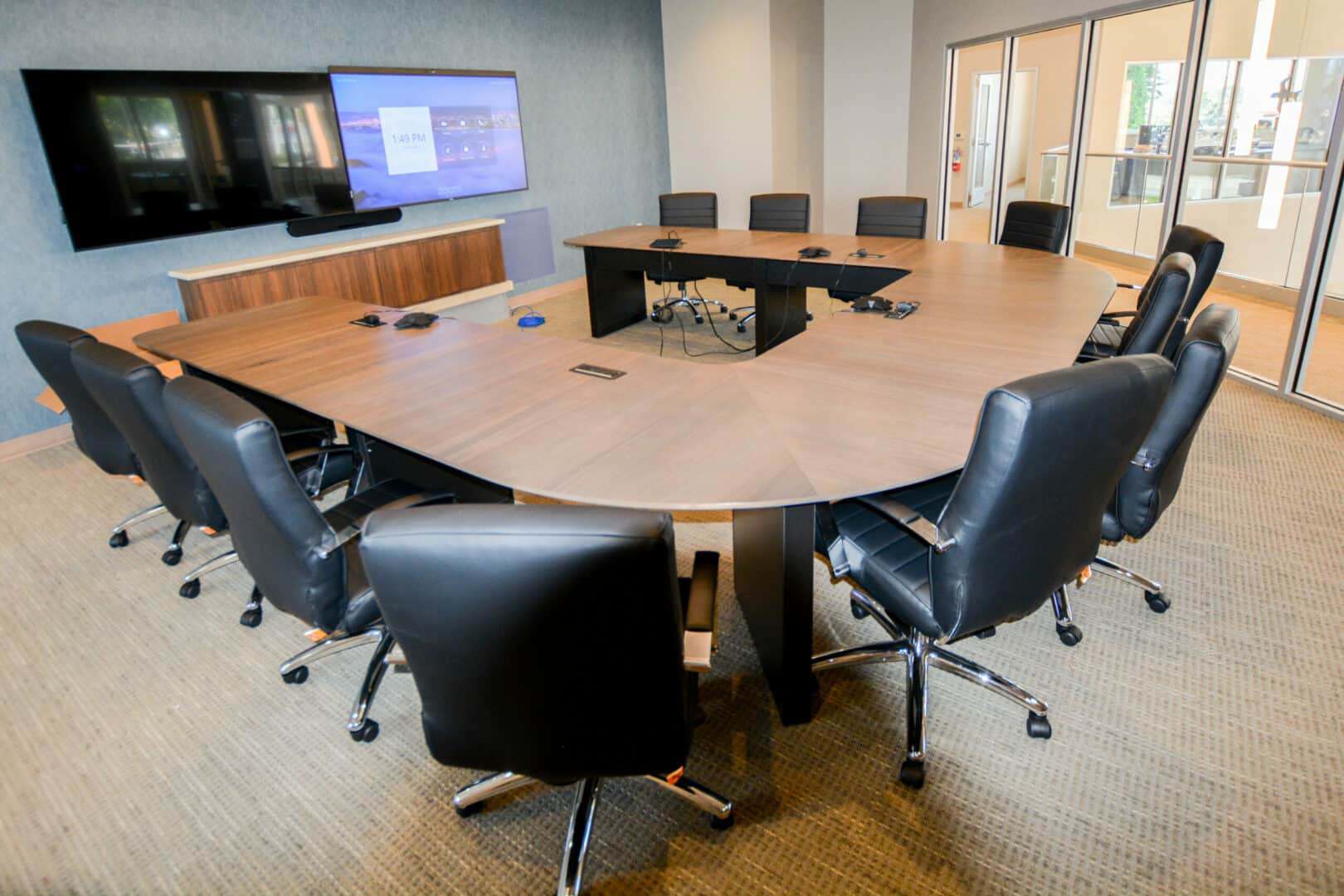 Modern conference room with large table and black leather chairs.