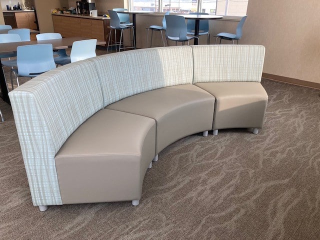 Modern curved lounge seating with beige and plaid fabric in office.