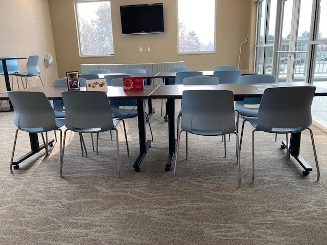 Modern meeting room with tables, chairs, and a wall-mounted TV.