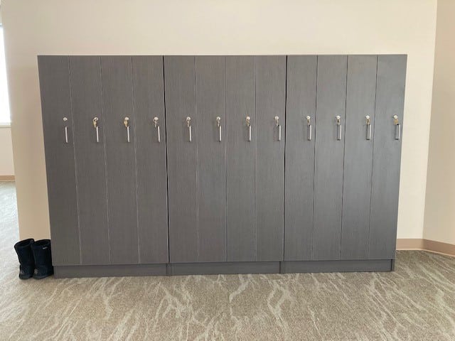 Row of grey lockers with silver handles in an office setting.