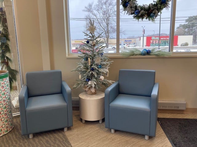 Two blue armchairs with a small decorated Christmas tree between them.