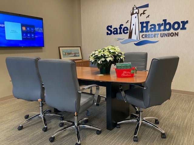 Meeting room with chairs, table, and Safe Harbor Credit Union logo.