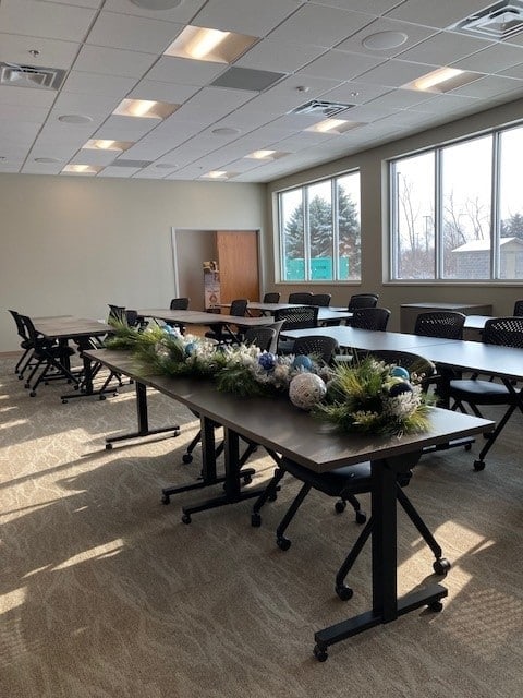 Bright conference room with large windows and tables decorated for a meeting.