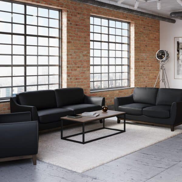 Contemporary office lounge with black sofas and large windows.