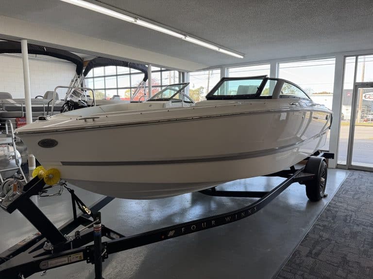 White motorboat on a trailer indoors at Hall's Sport Center, showroom setting.