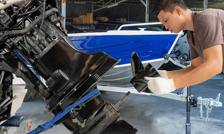 Close-up of technician repairing boat engine at Hall's Sport Center, expert boat motor service.