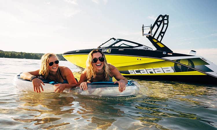 Two women enjoying speedboat ride and water sports on lake.
