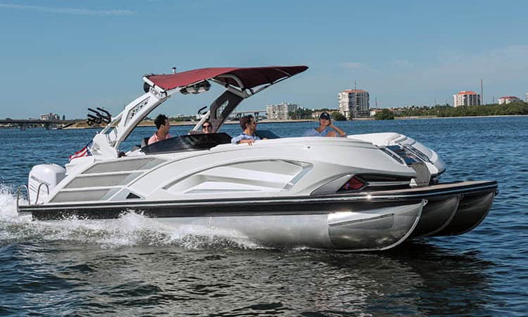 High-end luxury pontoon boat on water with people enjoying boat ride.