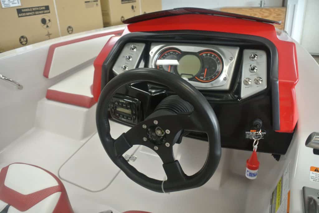 Close-up of a children's ride-on boat dashboard with steering wheel and speedometer, ideal for kids' outdoor activities.