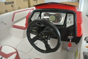 Close-up of a children's ride-on boat dashboard with steering wheel and speedometer, ideal for kids' outdoor activities.