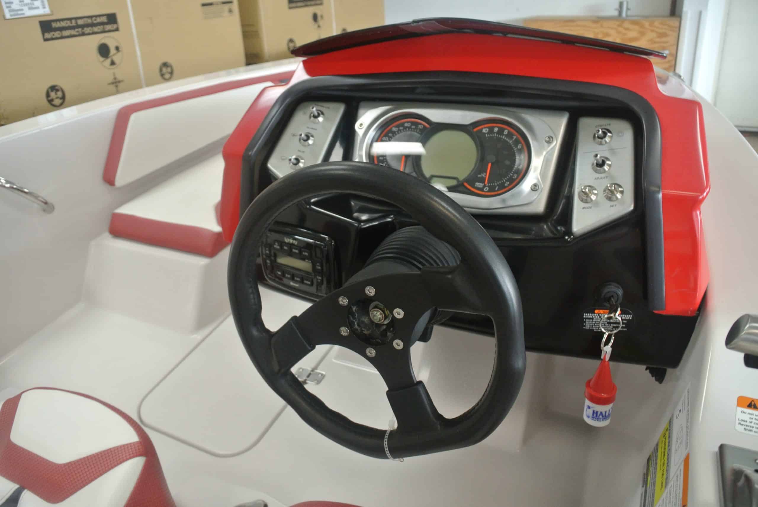 Close-up of a children's ride-on boat dashboard with steering wheel and speedometer, ideal for kids' outdoor activities.