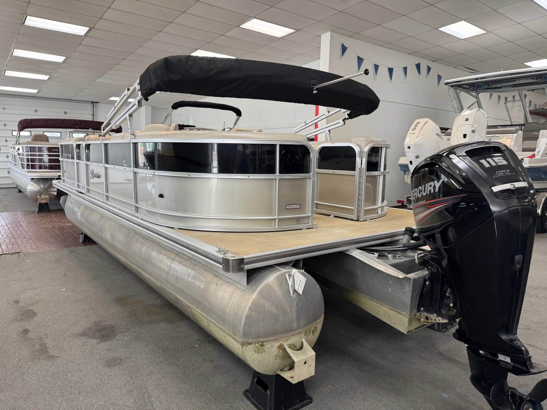 Pontoon boat with Mercury outboard motor and canopy.