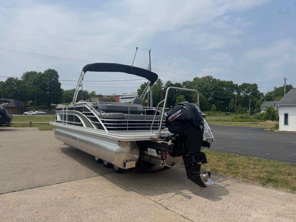 Pontoon boat with Mercury outboard motor on display at Hall's Sport Center. Perfect for leisure and watersports.