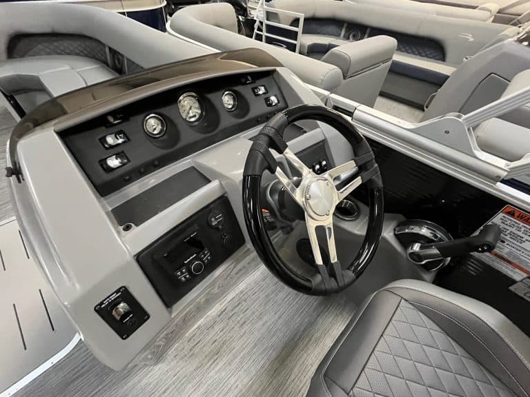 Modern pontoon boat dashboard with steering wheel and gauges.