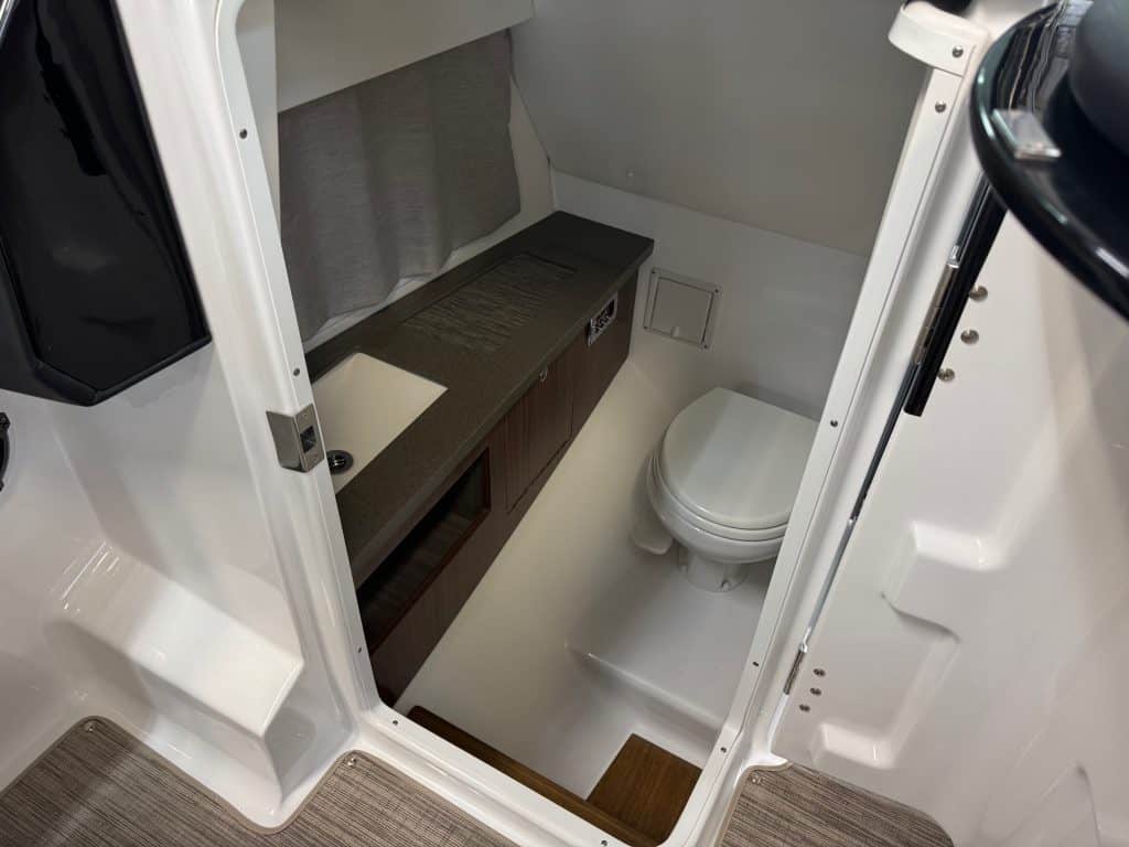 Compact boat bathroom with toilet and storage.