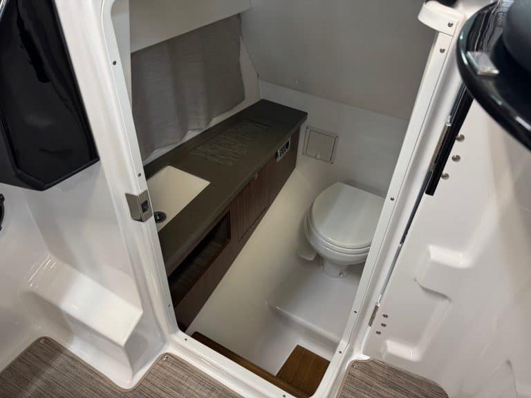 Compact boat bathroom with toilet and storage.