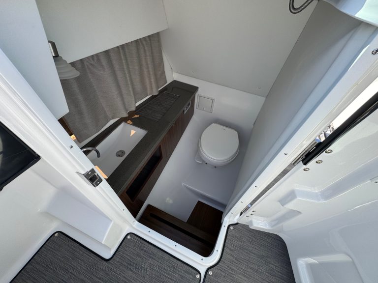 Boat bathroom with toilet and sink at Hall's Sport Center dealership.
