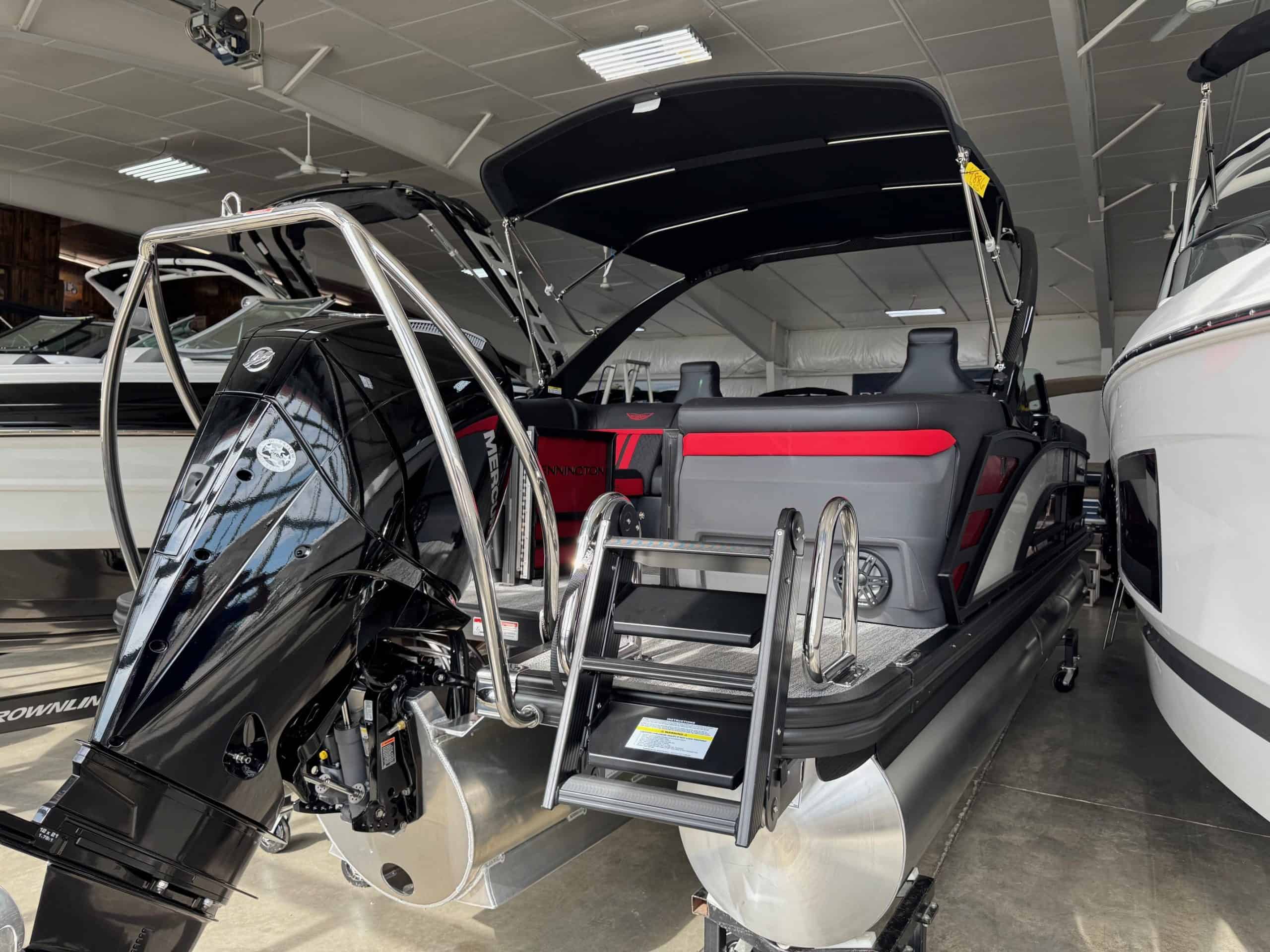 Bennington 24 MFB pontoon boat with outboard motor inside Hall's Sport Center showroom.